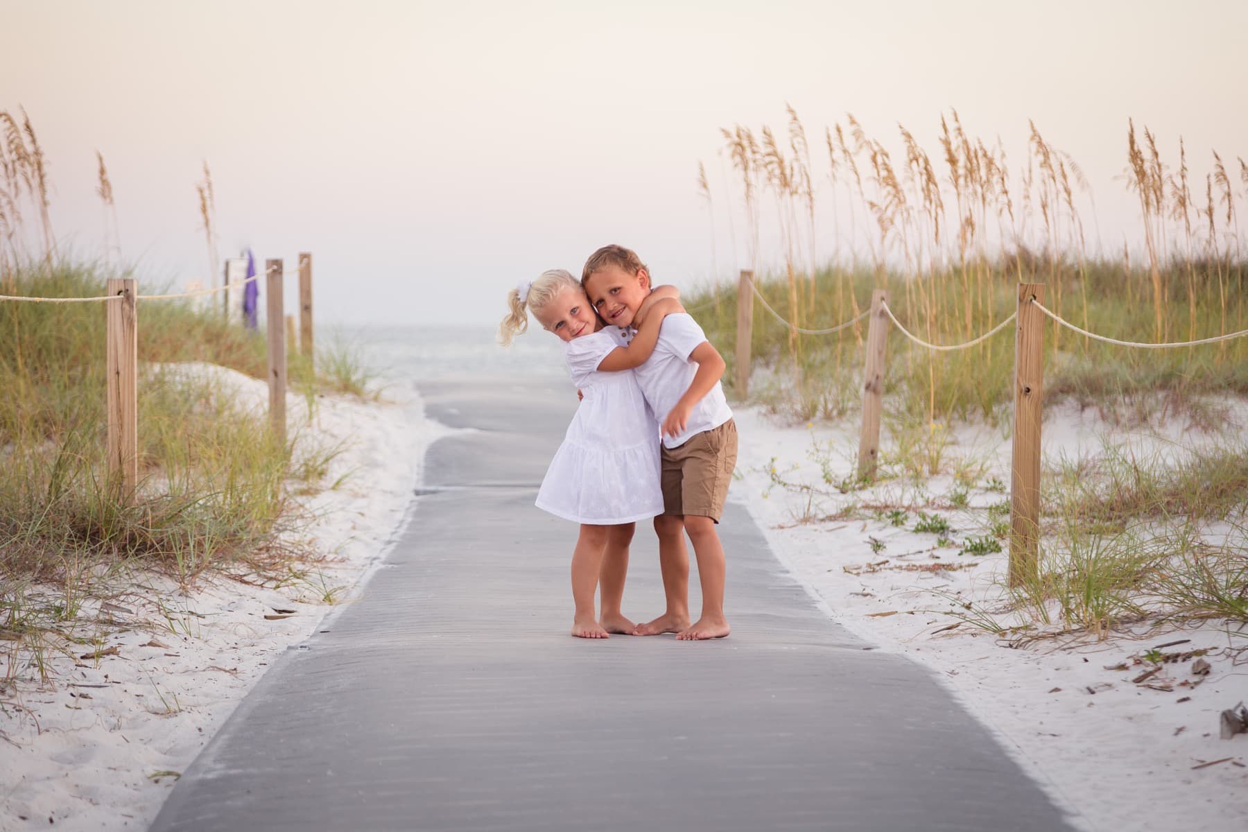 Two children embracing on a beach path, photographed by Dan Brugere